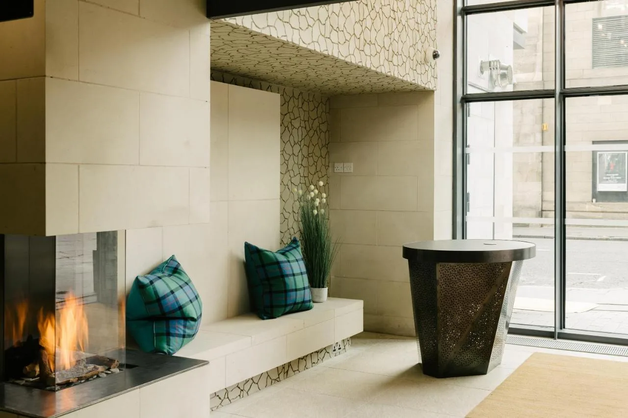 a fireplace in a living room with two blue pillows at Market Street hotel in Edinburgh